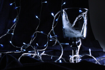 Empty glass with feathers flying on dark background