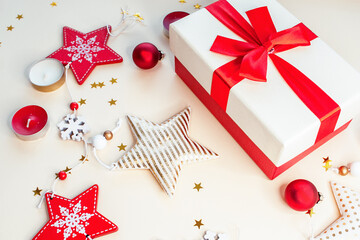 Christmas composition, close-up. A gift box with a red ribbon, decorations, garlands of lanterns and candles. new year. Space for text. Beige background.