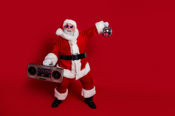 Photo of crazy old man hold boombox glowing ball dance disco wear santa hat costume isolated red...