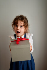 Little happy girl with a funny face surprised by a Christmas gift .Happy laughing child girl with Christmas gift at home. Christmas surprise. Christmas holidays concept, New Years Eve