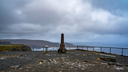 stürmisches Wetter am Nordkap, Wellen brechen an der Küste mit Schaumkronen und Gischt. der Sturm peitscht die Wellen ans Land und die dunklen Wolken jagen über das dunkelblaue Meer. Ozean, nördlich 