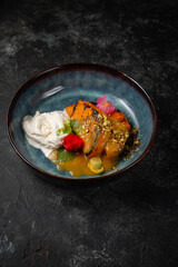 Grilled pumpkin steak in a blue plate on a dark table