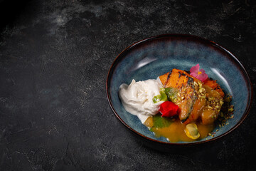 Grilled pumpkin steak in a blue plate on a dark table