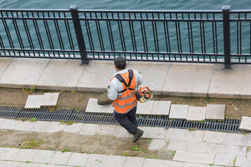 A worker mows the grass on the destroyed river embankment.