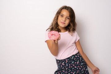 Portrait of a little smiling girl brunette with appetizing donuts in her hand