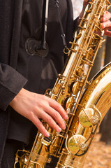 A woman plays the saxophone in an autumn park. Close-up of the golden saxophone