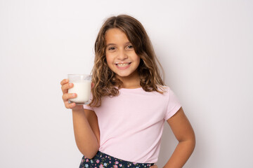 Smiling little girl with a glass of milk isolated over white background.