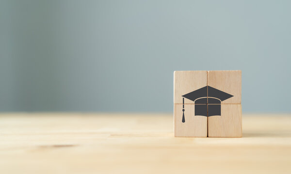 Graduation from university, education, diploma concept. Happiness cheerful feeling, Commencement, Graduation day. The wooden cubes with graduation cap on beautiful grey background and copy space.