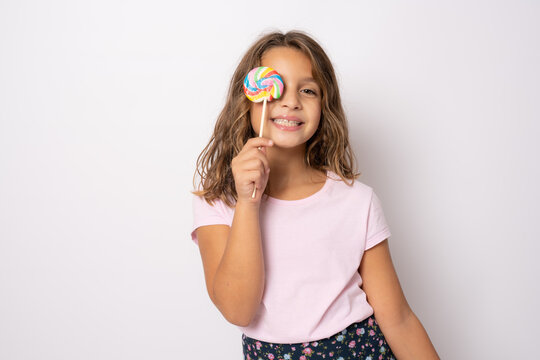 Beautiful amazed little girl with lollipop isolated over white background.
