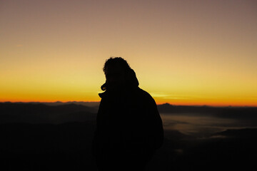 Woman watching the sunrise from the top of the mountain