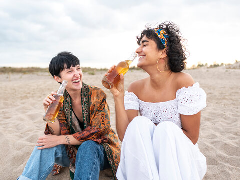 Happy diverse women drinking beer on beach