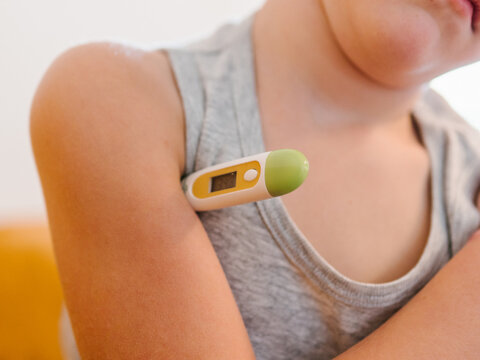 Anonymous sick child measuring temperature at home