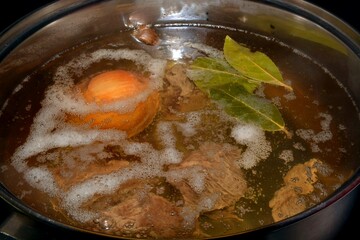 Meat broth with whole onion and bay leaf.