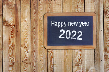 happy new year 2022 written on a slate on rustic plank background