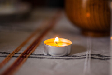 Photo of a burning candle on a table with a tablecloth
