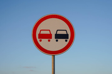 Photo of a road round sign with red and black cars on a background of blue sky