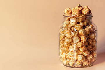 caramel popcorn in a glass jar with a place for text on the background