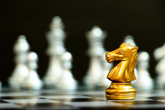 Gold knight in chess game face with the another silver team on black background (Concept for company strategy, business victory or decision)