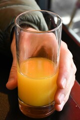 Verre de jus d'orange tenu à la main