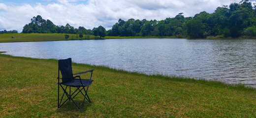 Fototapeta premium Chairs sitting on the shore of a mountain lake on the green grass.