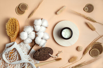 Fototapeta na wymiar white cream in a round box and bath accessories on beige background