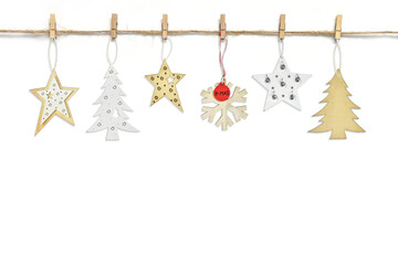 various  wood pendants hanging on clothespins on a rope thread on a white background. Fir trees,...