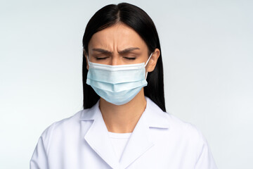 Headache, sadness, confusion or concentration. Portrait of worry alone woman doctor in white suit standing and closed her eyes. Indoor studio shot isolated on white background