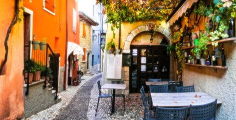 Fototapeta na wymiar Charming old narrown streets of Italian villages. Malcesine, Garda lake, Italy. Autumn colors, cosy street bars