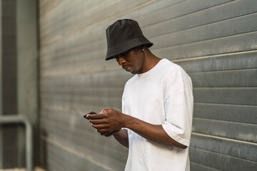 Chico negro atletico con smartphone posando en la calle