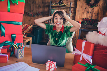 Photo of amazed shocked happy woman santa helper christmas sit desk laptop workplace indoors inside...