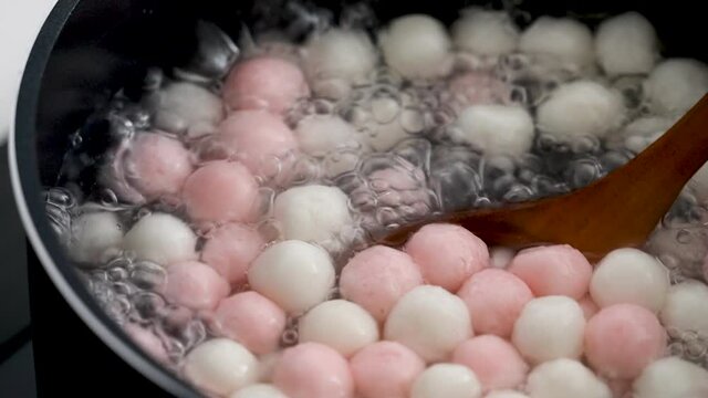 Boiling traditional little delicious red and white tangyuan, tang yuan, rice dumpling balls for Winter Solstice Festival food.