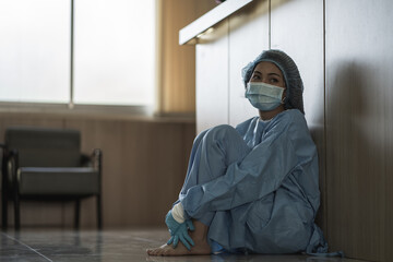 asian woman doctor wearing surgical face mask sitting on thr floor tired from work because impact...