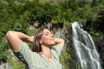Happy woman breathing and resting in a waterfall