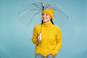 I like different weather. Young brunette woman wearing knitted hat and sweater holding transparent...