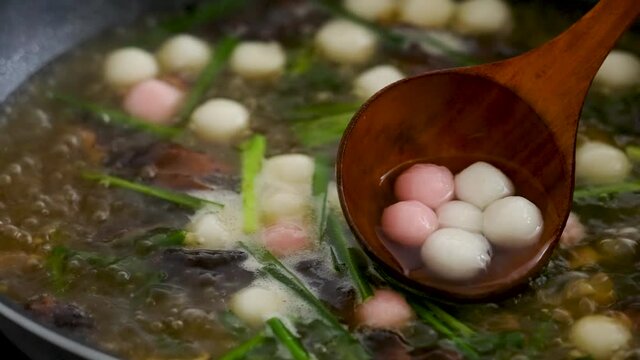 Boiling Taiwanese traditional Hakka savory little delicious red and white tangyuan, tang yuan, rice dumpling balls in the broth for Winter Solstice Festival food.
