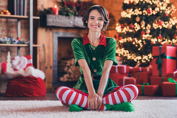 Photo of sweet funny young woman dressed green costume smiling celebrating new year sitting legs...