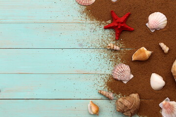 Seashells lie on the sand on a wooden background.