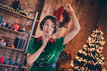 Photo of pretty shocked young woman dressed green costume smiling celebrating new year finger chin indoors room home house