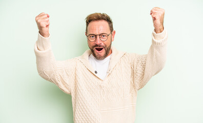 middle age handsome man celebrating an unbelievable success like a winner, looking excited and...