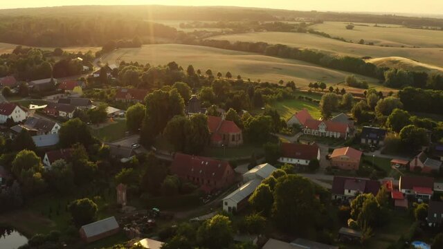 Aerial View in summer over a small village in Mecklenburg-Vorpommern Germany. The fields are yellow and green and the sun is going down.