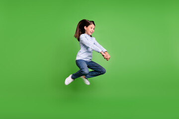 Photo of beautiful funky schoolgirl wear blue turtleneck jumping high riding horse smiling isolated green color background