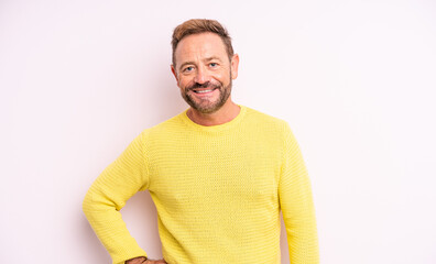 middle age handsome man smiling happily with a hand on hip and confident, positive, proud and...