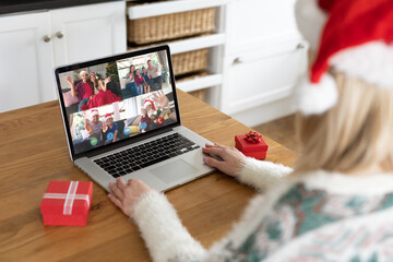 Caucasian woman on christmas laptop video call with diverse group of friends