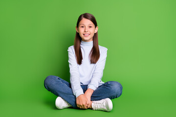 Fototapeta na wymiar Photo of charming pretty schoolgirl wear blue turtleneck sitting floor smiling isolated green color background