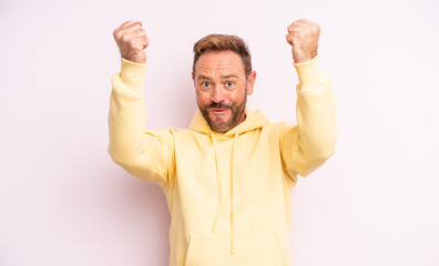 middle age handsome man celebrating an unbelievable success like a winner, looking excited and...