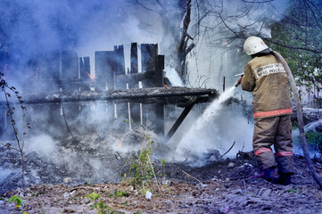 Firefighters with the inscription on the back in Russian "Fire protection" extinguish the fire on the fire
