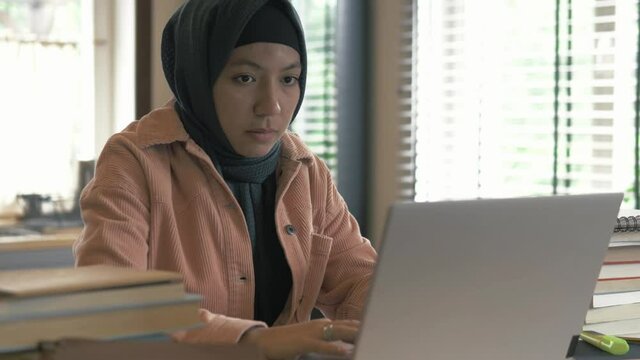 Concentrated focused woman in hijab using laptop. Muslim student girl study remote or work in the kitchen at home. Muslim islamic stylish freelancer woman 