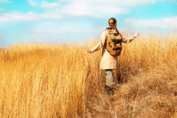 Warm autumn portrait of a girl outdoors. Unrecognizable woman traveler with backpack enjoying the view. 