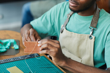 Cropped portrait of young African-American artisan working with leather in leatherworkers workshop, copy space - Powered by Adobe