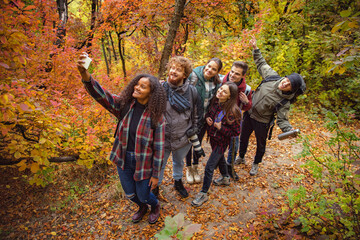 Group of young, joyful friends doing selfie while hiking, spending time togeter in the fores